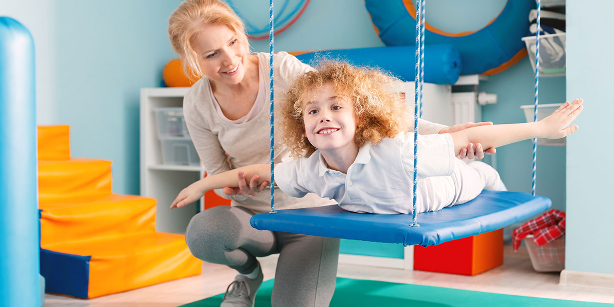 A boy on a therapy swing for sensory intergration.